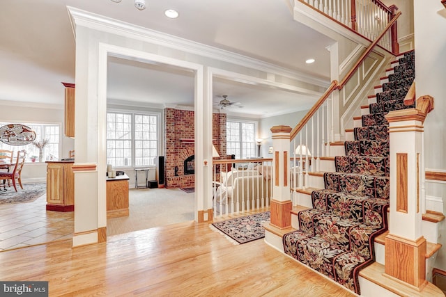 stairway with ceiling fan, plenty of natural light, wood finished floors, and ornamental molding