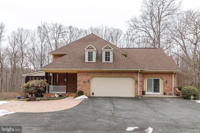 view of front of home with aphalt driveway, covered porch, brick siding, and roof with shingles