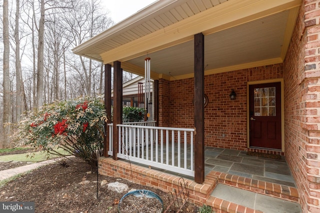 entrance to property with brick siding and a porch