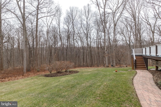 view of yard featuring stairs, a deck, and a wooded view