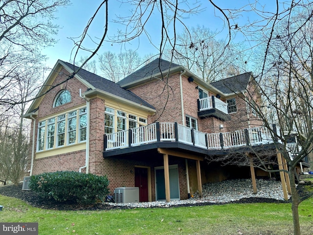 rear view of house featuring brick siding, a wooden deck, and a yard