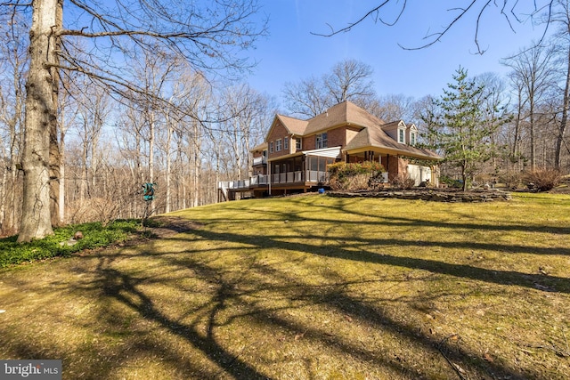 view of side of home featuring brick siding, a lawn, and a wooden deck