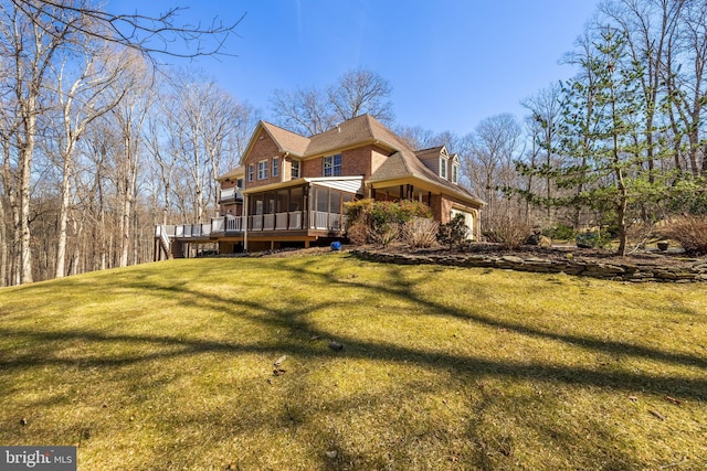 rear view of house with a yard, brick siding, and a sunroom