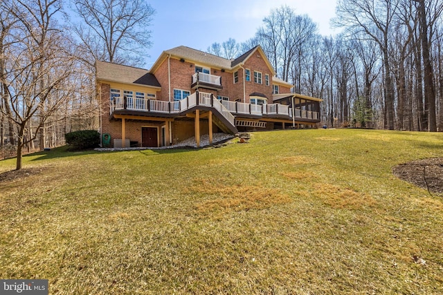 rear view of house with a wooden deck, brick siding, a lawn, and stairway