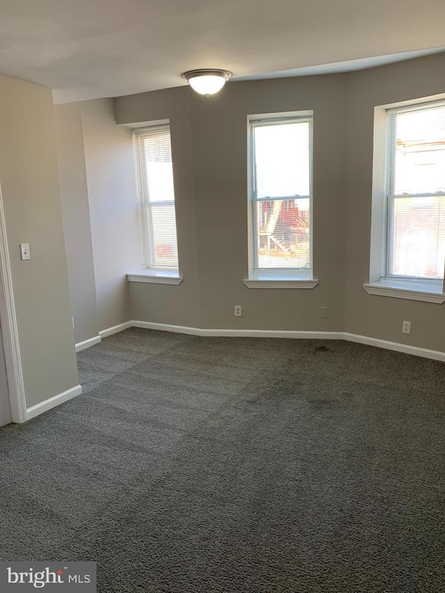 unfurnished room featuring dark colored carpet