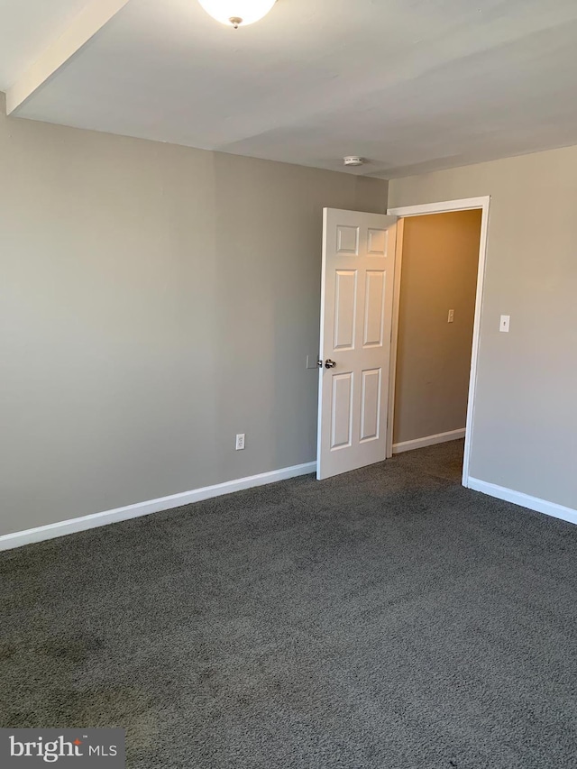 spare room with dark colored carpet