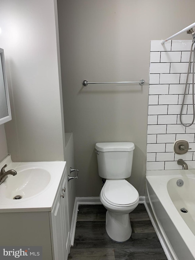 full bathroom with hardwood / wood-style flooring, vanity, tiled shower / bath, and toilet