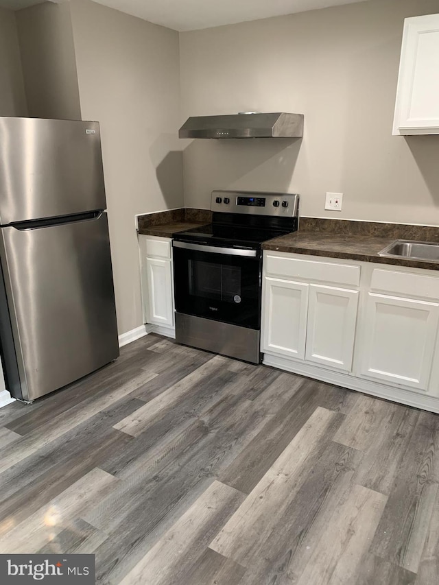 kitchen featuring white cabinetry, appliances with stainless steel finishes, dark hardwood / wood-style flooring, and wall chimney exhaust hood