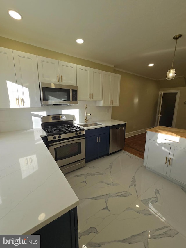 kitchen featuring hanging light fixtures, stainless steel appliances, sink, and white cabinets