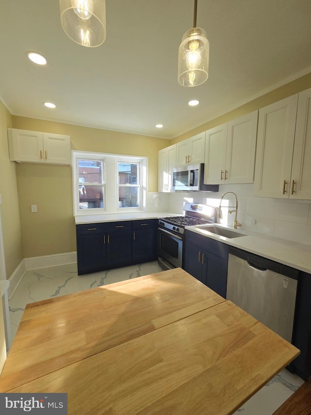 kitchen with stainless steel appliances, white cabinetry, sink, and decorative light fixtures