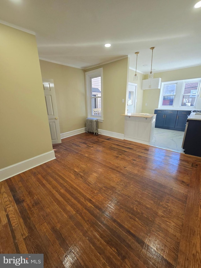 unfurnished living room with ornamental molding, dark wood-type flooring, and radiator heating unit