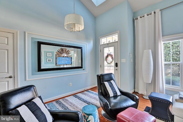 sitting room featuring wood-type flooring and lofted ceiling with skylight