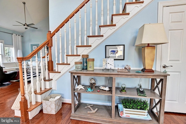 stairs with ceiling fan, hardwood / wood-style floors, and a high ceiling