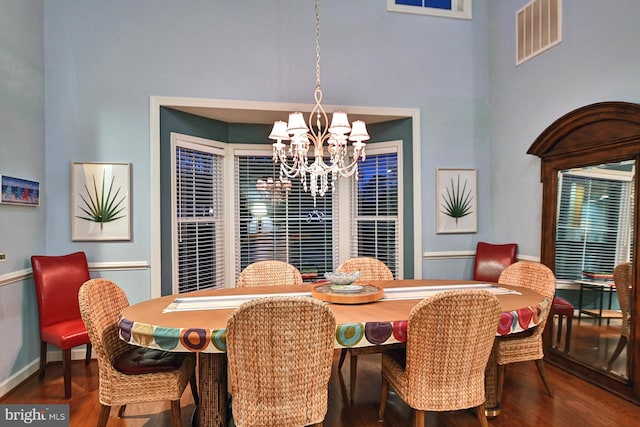 dining room featuring a towering ceiling, dark hardwood / wood-style floors, and a chandelier