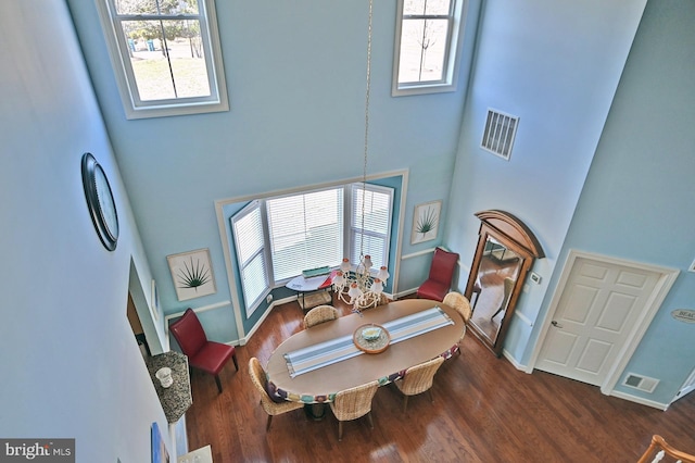 dining space featuring dark wood-type flooring and a towering ceiling