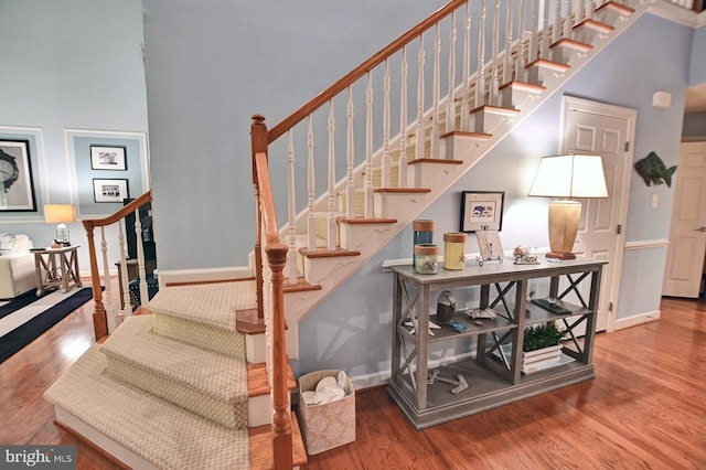 stairway with hardwood / wood-style flooring and a towering ceiling