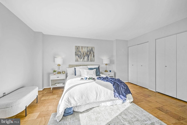 bedroom featuring multiple closets and light parquet flooring