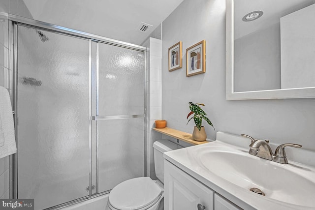 bathroom featuring vanity, a shower with shower door, and toilet