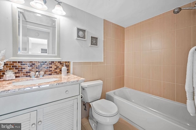 full bathroom with tiled shower / bath, vanity, toilet, and tile walls