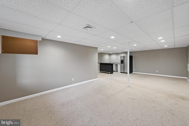 basement featuring indoor bar, carpet floors, a paneled ceiling, and stainless steel fridge with ice dispenser