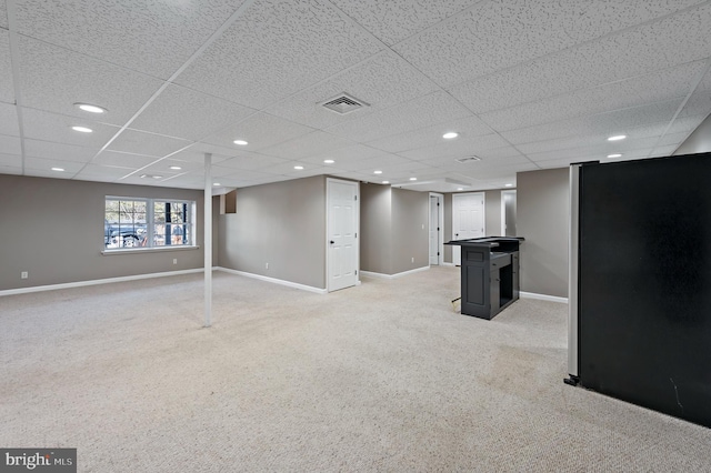 basement featuring a paneled ceiling and carpet floors