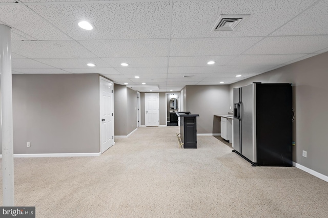 basement with light colored carpet, stainless steel fridge with ice dispenser, and a drop ceiling