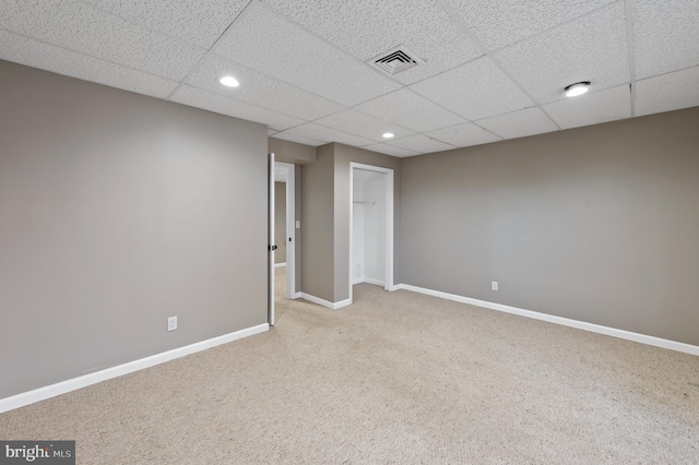 carpeted empty room featuring a drop ceiling