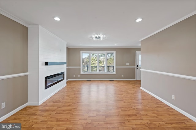 unfurnished living room featuring ornamental molding, a large fireplace, and light hardwood / wood-style flooring