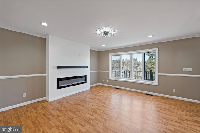 unfurnished living room featuring crown molding, light hardwood / wood-style flooring, and a large fireplace