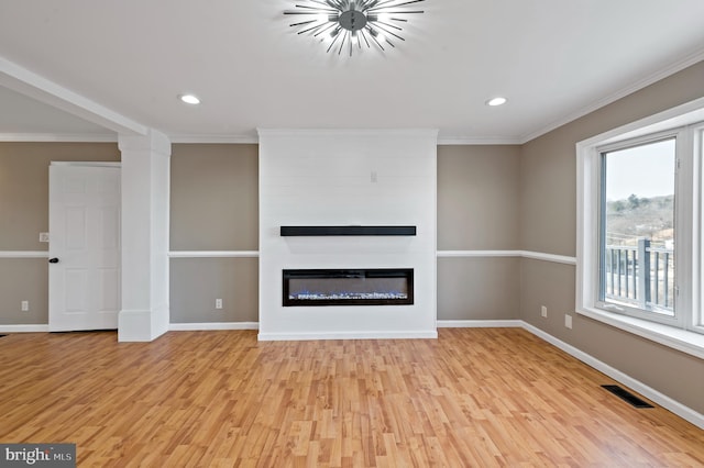 unfurnished living room with a fireplace, ornamental molding, and light hardwood / wood-style floors