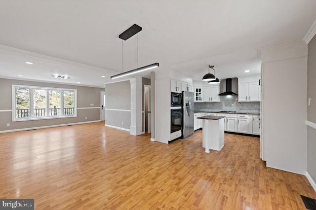 kitchen with wall chimney range hood, white cabinetry, backsplash, hanging light fixtures, and black appliances