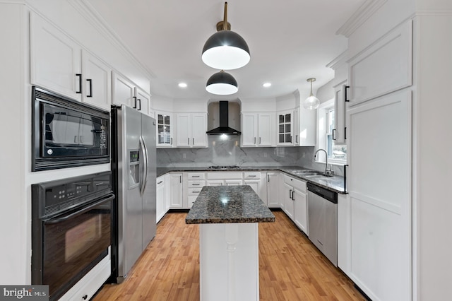 kitchen featuring wall chimney range hood, sink, white cabinetry, black appliances, and a kitchen island