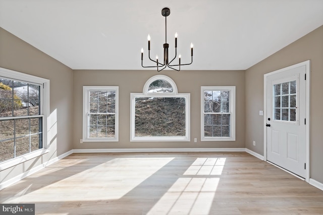 unfurnished dining area featuring a notable chandelier, a wealth of natural light, and light hardwood / wood-style floors