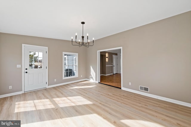 unfurnished dining area featuring an inviting chandelier and light hardwood / wood-style flooring