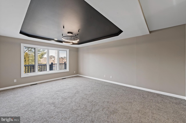 carpeted empty room featuring a raised ceiling