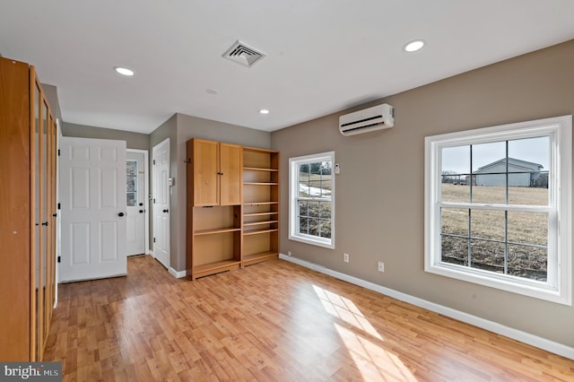 unfurnished bedroom featuring a closet, light hardwood / wood-style flooring, and an AC wall unit