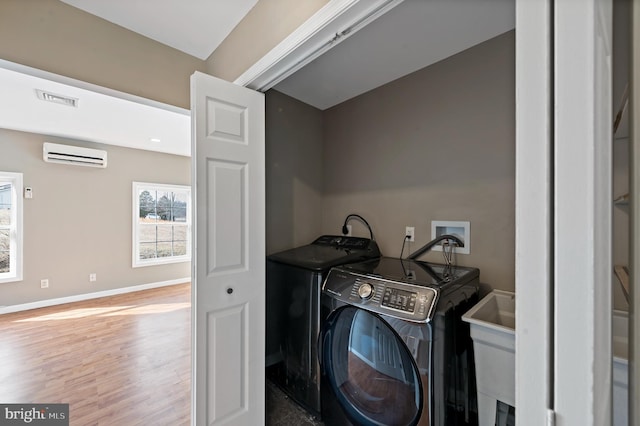 clothes washing area with independent washer and dryer, sink, hardwood / wood-style floors, and a wall unit AC