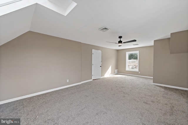 empty room featuring carpet flooring, ceiling fan, and a skylight