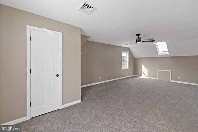 additional living space featuring carpet, vaulted ceiling with skylight, and ceiling fan