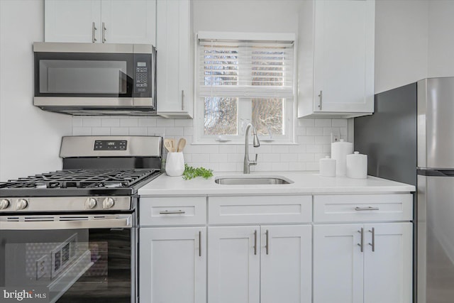 kitchen featuring sink, decorative backsplash, white cabinets, and appliances with stainless steel finishes