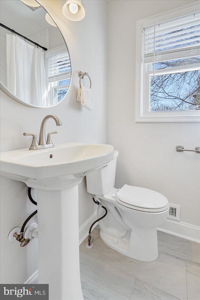 bathroom featuring a wealth of natural light, curtained shower, and toilet