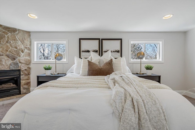 bedroom with multiple windows, a fireplace, and carpet