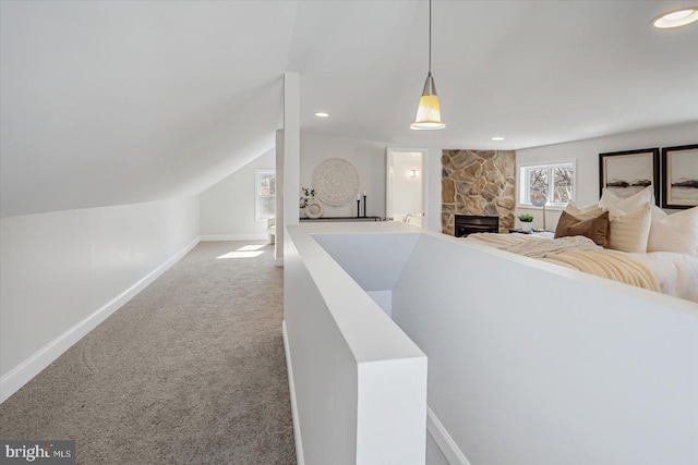 interior space featuring lofted ceiling and a stone fireplace