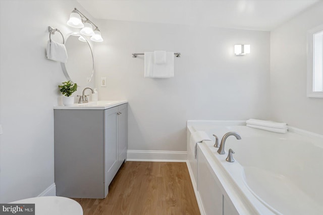 bathroom featuring vanity, wood-type flooring, and a tub to relax in