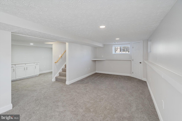 basement featuring light colored carpet and a textured ceiling