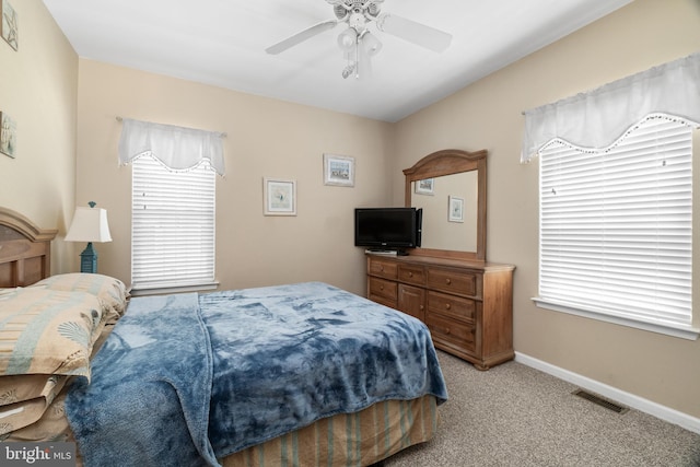 carpeted bedroom featuring multiple windows and ceiling fan