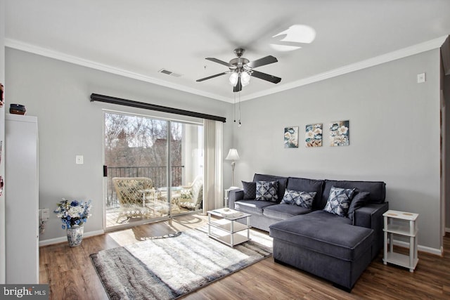 living room with dark wood-type flooring, ceiling fan, and crown molding