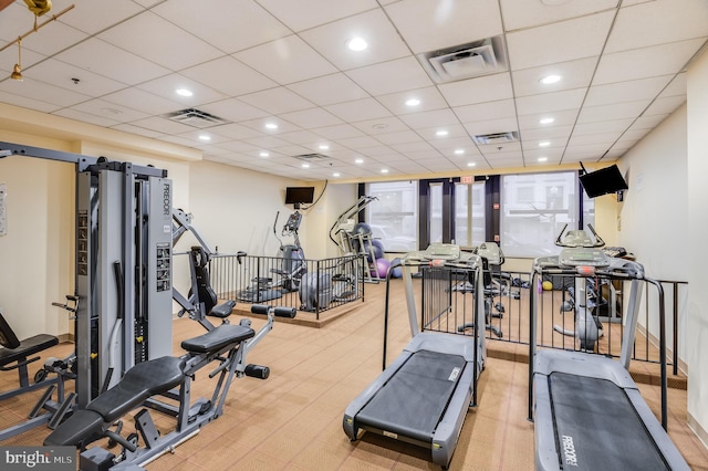 gym with a paneled ceiling and a barn door