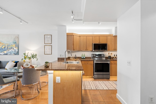 kitchen with sink, rail lighting, stainless steel appliances, light tile patterned flooring, and kitchen peninsula