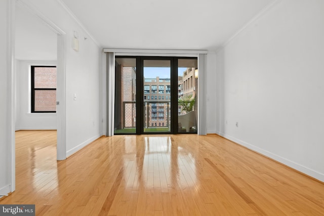 spare room featuring ornamental molding, floor to ceiling windows, and light wood-type flooring